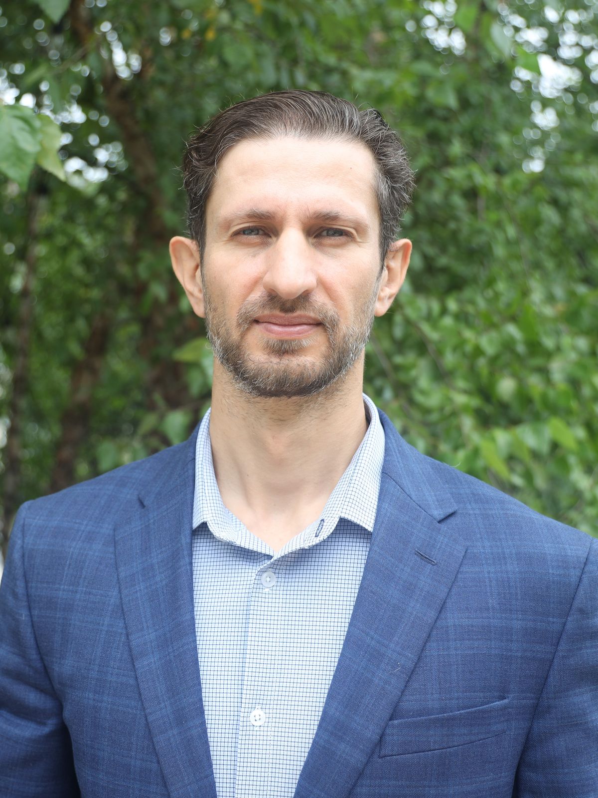 a man in a suit standing in front of a tree