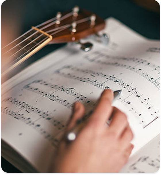 a person writing music notes on a sheet of music