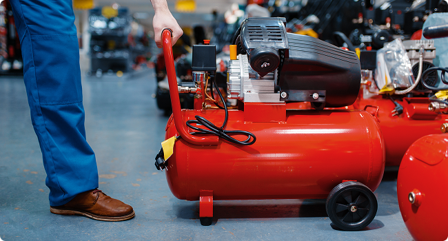a man is standing next to a red air compressor