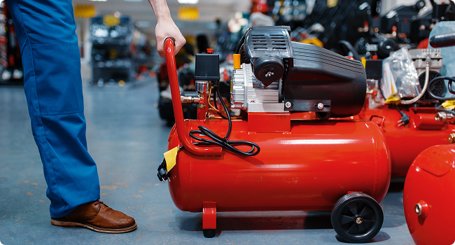 a man is standing next to a red air compressor